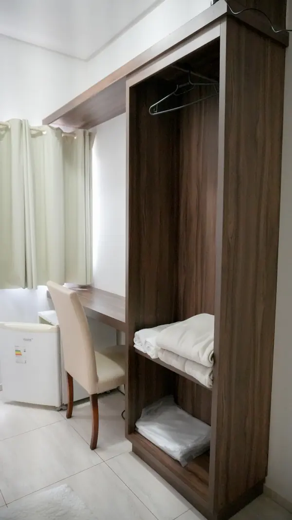 Armário aberto, mesa de trabalho e frigobar